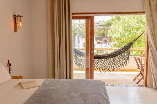 a bed and a hammock in a room with a balcony at Casa Suiça Brasileira in Jericoacoara