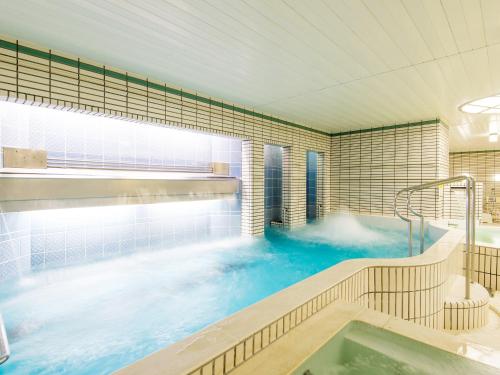 a large blue bath tub in a room with aitating at Art Hotel Asahikawa in Asahikawa