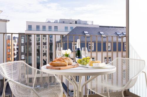 a table with bread and wine glasses on a balcony at The Central City - Luxury Serviced Residence in Luxembourg