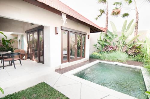 a villa with a swimming pool in front of a house at Villa Puspa in Tanah Lot