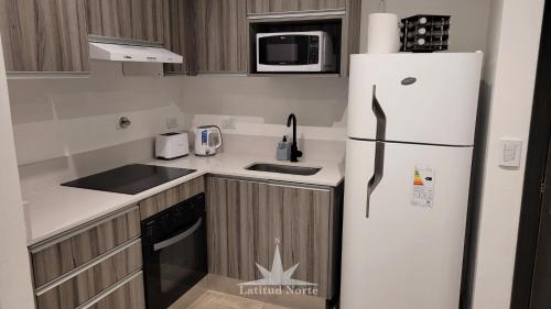 a kitchen with a refrigerator and a microwave at Departamento 318 en complejo premiun de Pinamar Norte in Pinamar