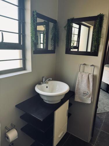 a bathroom with a sink and two mirrors at Annie's Place in Kempton Park