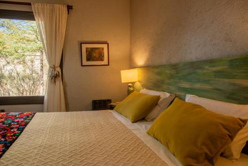 a bedroom with a bed with yellow pillows and a painting at San Ignacio Estancia Andina in El Challao