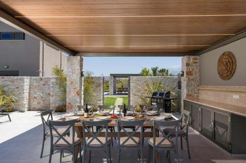 a patio with a table and chairs and a grill at Imperium Luxury Villas-Sauna, Jacuzzi, Heated Pool & Gym-Chania in Kato Galatas