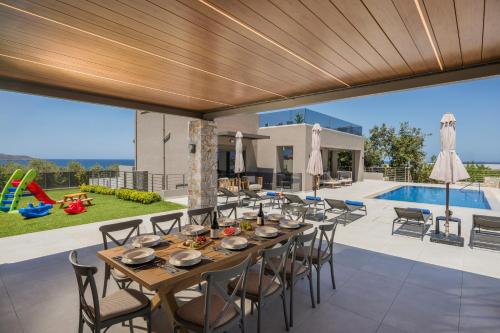 an outdoor dining area with a table and chairs and a pool at Imperium Luxury Villas-Sauna, Jacuzzi, Heated Pool & Gym-Chania in Kato Galatas
