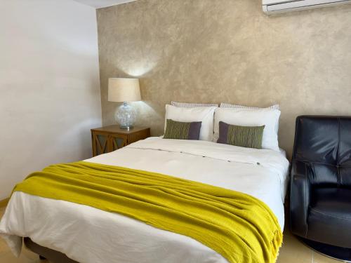 a bedroom with a bed with a yellow blanket on it at Villa Esterito in La Paz