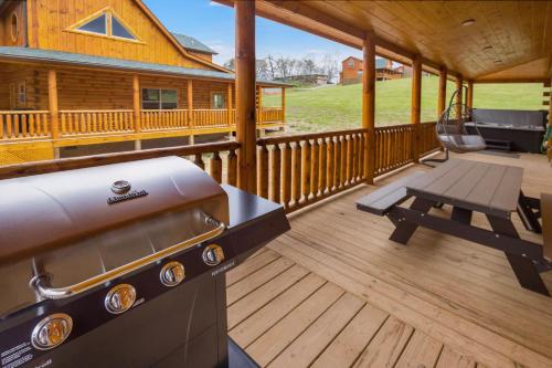 a porch of a log cabin with a grill and a swing at New! Indoor Pool/PS 5/Hot tub/Parkway in Pigeon Forge