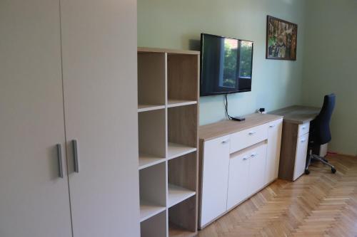 a room with a desk with a computer and a television at Monica's Apartman in Szeged