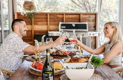 a man and woman drinking wine at a table with food at The Harmony Retreat in Murrays Beach