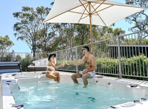 a man and a woman sitting in a swimming pool at The Harmony Retreat in Murrays Beach