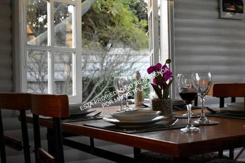 a wooden table with glasses and a plate on it at Piscina Climatizada Privada, Cabaña, Quincho, Limache in Limache