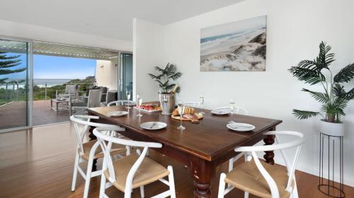 a dining room with a wooden table and white chairs at Jones Waterfront Beach Escape in Kiama Downs