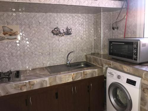 a kitchen with a washing machine and a microwave at Maison Samy in Ifrane