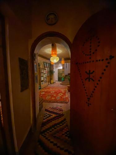 a hallway with a door and a room with a rug at Auberge Ayouze in Aït Ben Haddou