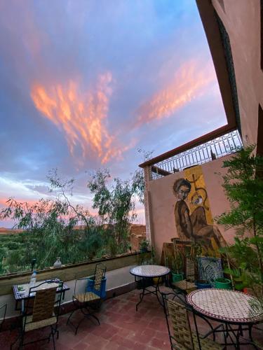 a patio with tables and chairs and a mural at Auberge Ayouze in Aït Ben Haddou