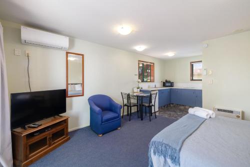 a bedroom with a bed and a tv and a blue chair at 112 on Beach in Kaikoura