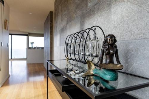 a statue of a mermaid sitting on a glass table at Ava - Luxe Oceanfront Beach House in Falmouth