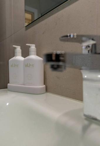 a bathroom with two soap bottles on a bathroom sink at Ava - Luxe Oceanfront Beach House in Falmouth