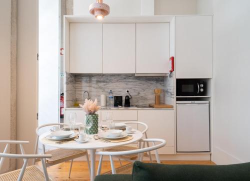 a white kitchen with a table and chairs at Habitatio - Aliados by LuxiStay in Porto