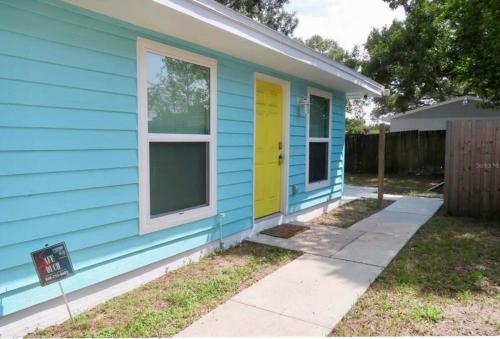 a blue house with a yellow door at Nataj suites at Tampa in Tampa