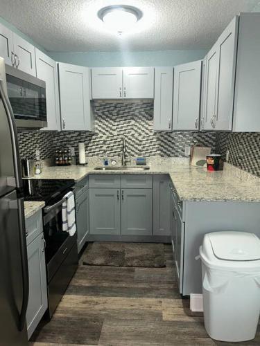 a kitchen with white cabinets and a sink and a toilet at Nataj suites at Tampa in Tampa
