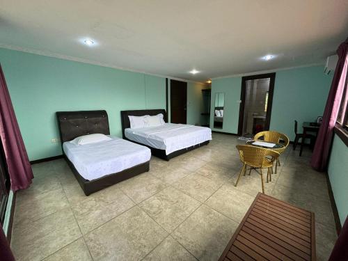 a bedroom with two beds and a table and chairs at Myoldhouse in Lahad Datu