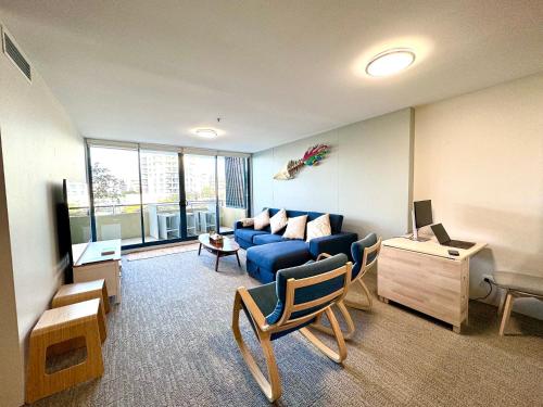 a living room with a blue couch and a table at Ocean View Private Cronulla Apartment in Cronulla