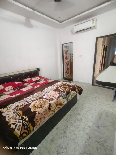 a bedroom with a bed with a floral bedspread at Guest house Khatu Shyam Ji in Khātu