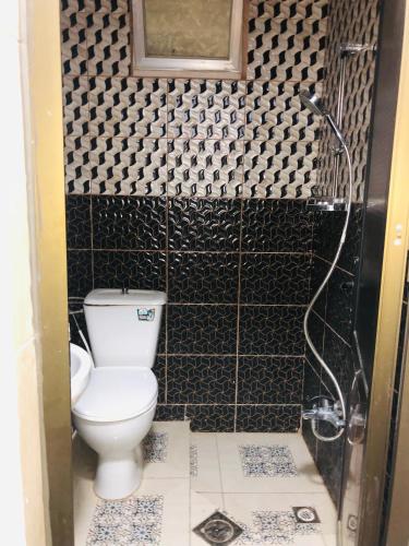 a bathroom with a toilet and black and white tiles at شاليه رضوى in Al Bunayyāt ash Shamālīyah