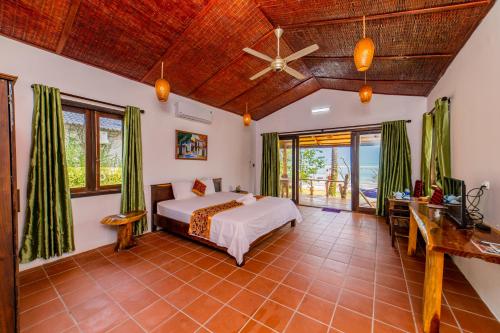 une chambre avec un lit et un ventilateur de plafond dans l'établissement Dugong Resort Phu Quoc, à Duong Dong