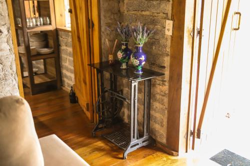 a table with a purple vase on it in a room at Chalé Casa de Pedra, Vivenda Serra Velha, Chalés de Montanha in Timbe do Sul