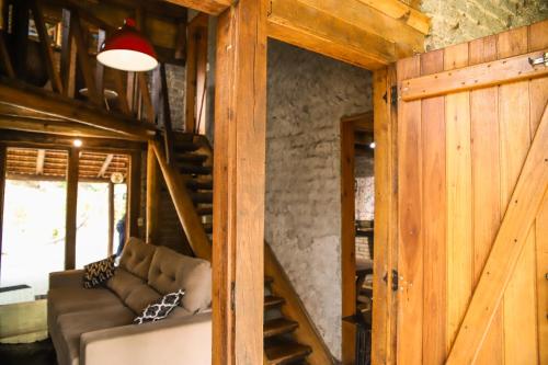 a living room with a couch and a wooden wall at Chalé Casa de Pedra, Vivenda Serra Velha, Chalés de Montanha in Timbe do Sul