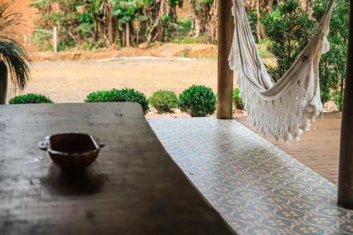 a hammock with a bowl sitting on a table at Chalé Casa de Pedra, Vivenda Serra Velha, Chalés de Montanha in Timbe do Sul