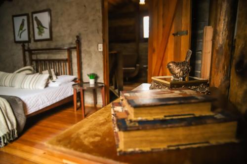 a room with a bed and a table with a book at Chalé Casa de Pedra, Vivenda Serra Velha, Chalés de Montanha in Timbe do Sul
