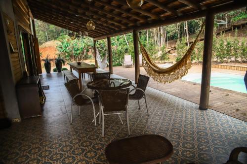 a room with a hammock and a table and chairs at Chalé Casa de Pedra, Vivenda Serra Velha, Chalés de Montanha in Timbe do Sul