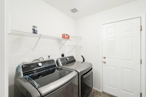 a washer and dryer in a white room with a door at Spacious 4BR w Game Room - 15 min to Seaworld in San Antonio