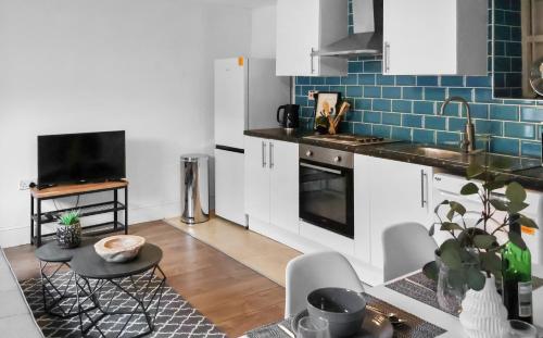 a kitchen with white cabinets and blue tiles at Morpeth City Centre Home in Morpeth