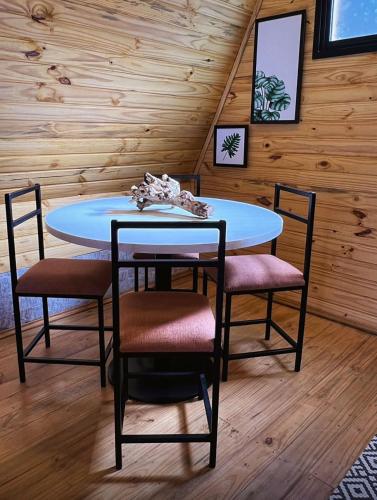 a table and chairs in a room with wooden walls at Chalés Laraland in Campos do Jordão