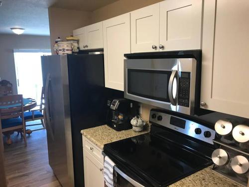 a kitchen with a microwave and a black refrigerator at 3Bed 2Bath Spacious-LakeHomeAceLoc4milesLEGOLAND in Cypress Gardens