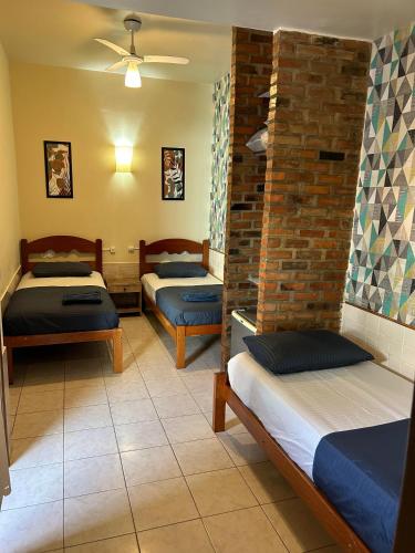 a room with three beds and a brick wall at Pousada Brisa da Praia in Arraial do Cabo