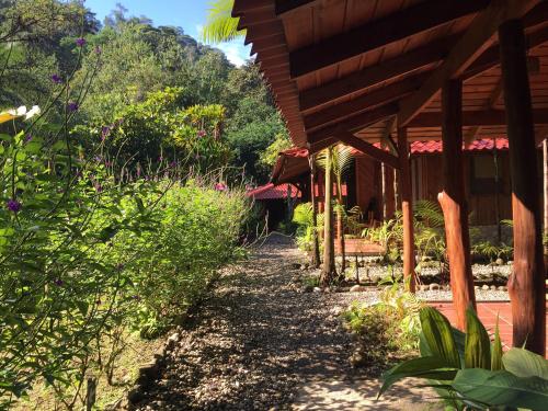 a path next to a wooden house with trees at Esquinas Rainforest Lodge in Golfito