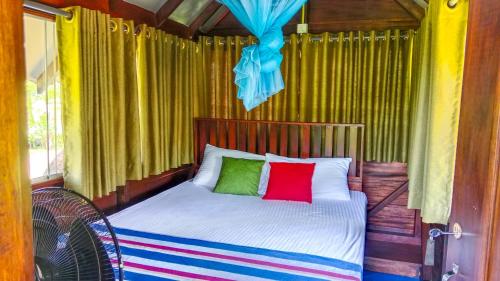 a bed with two colorful pillows in a room at Pride Rock Villa & Tree House in Sigiriya