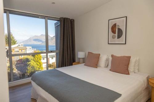 a bedroom with a large bed and a large window at Opuke House- Free Parking- Lake views- BBQ- Spa in Queenstown
