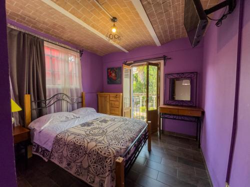 a bedroom with purple walls and a bed and a mirror at Vista Reforma in Guanajuato