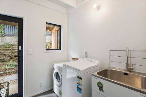 a white laundry room with a washing machine and a sink at Lake and Mountain Views - Central Queenstown in Queenstown