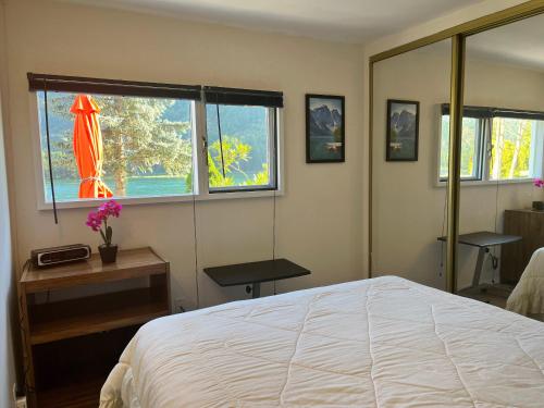 Un dormitorio con una cama y dos ventanas. en Waterfront, Mountainview House in Castlegar, en Castlegar