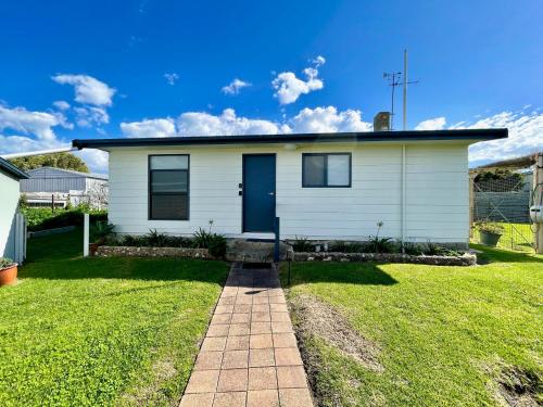 a white house with a blue door on a lawn at Kangaroo Island Seabright Garden Cottage in Kingscote