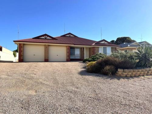 a house with two garage doors on a gravel driveway at Hughes by the Sea in Port Moonta