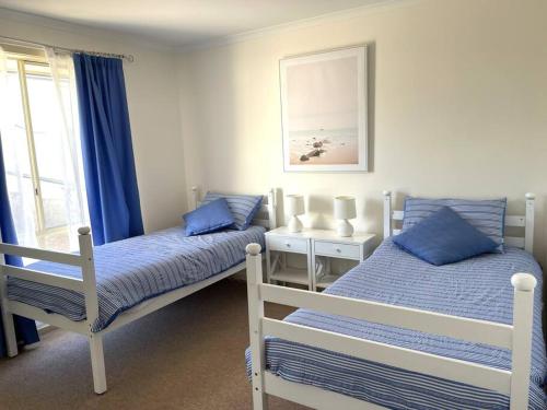 two beds in a bedroom with blue and white at Hughes by the Sea in Port Moonta