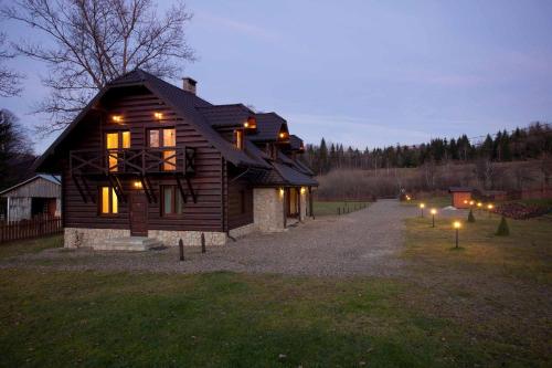a wooden house with lights in the yard at Dom Gościnny Borsuczyna in Wetlina